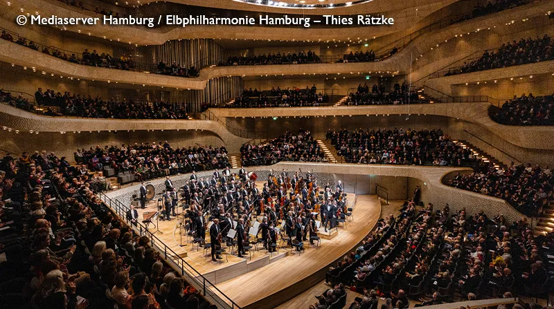 Orchester im Großen Saal der Elbphilharmonie vor voll besetzten Rängen