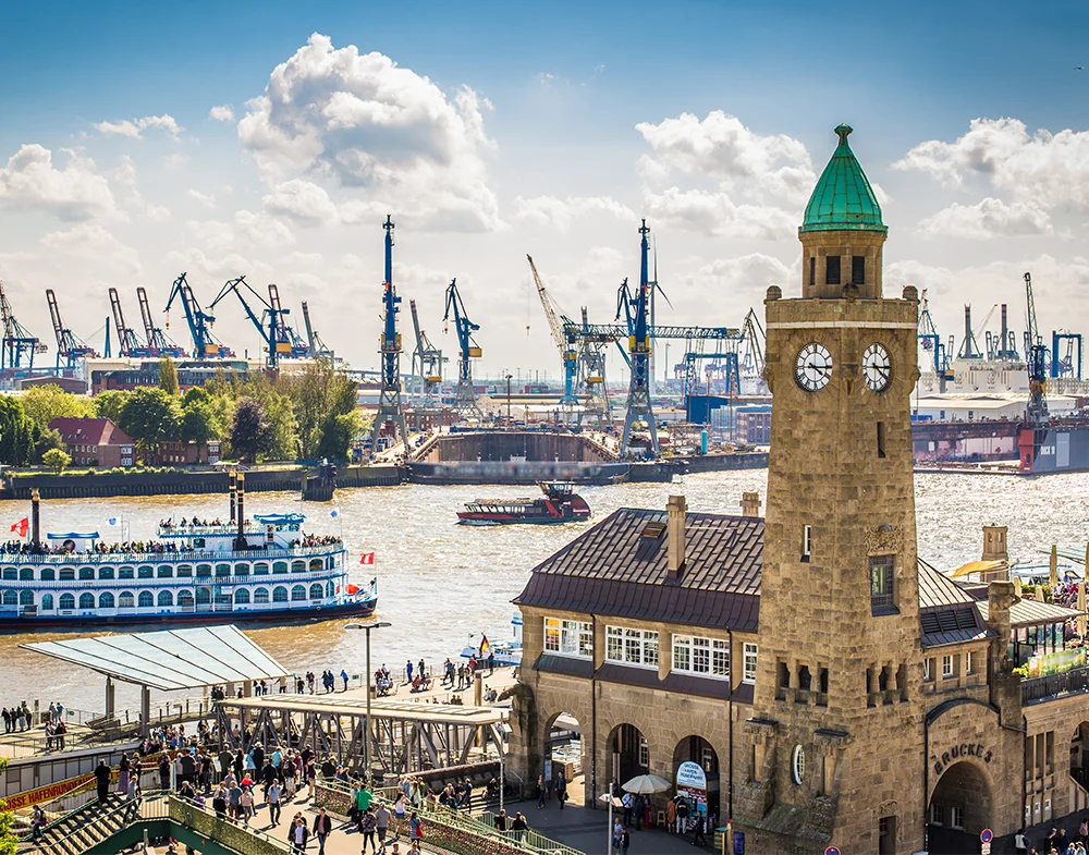 Hamburg Landungsbrücken with clock tower, sightseeing boats and harbour cranes