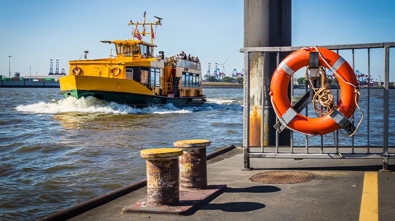 Gelbe Hafenfähre auf der Elbe mit Rettungsring am Anleger